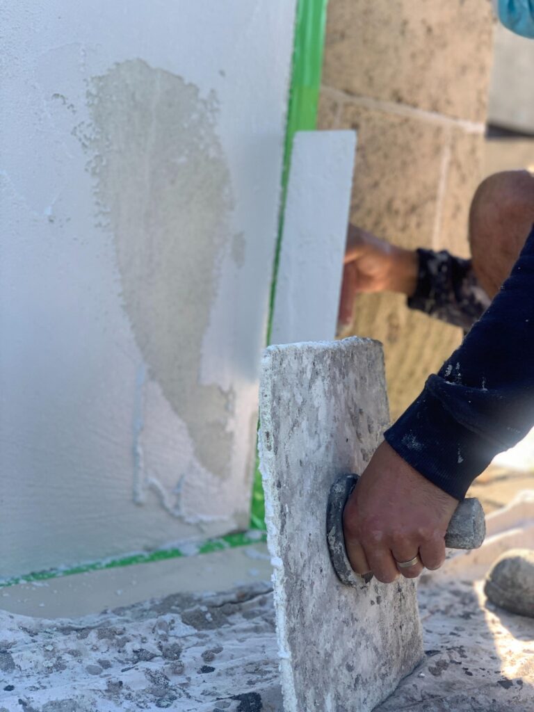 Sand and cement render being applied to a block wall